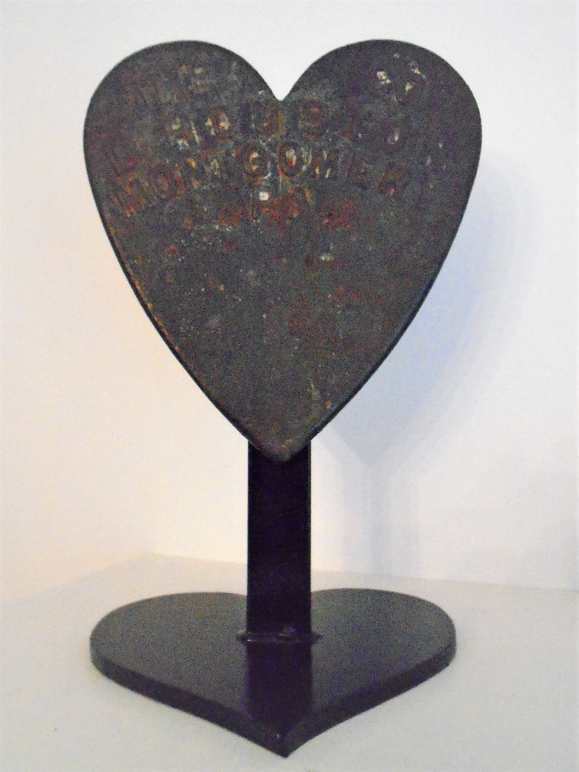 A CAST IRON WEIGHT IN THE SHAPE OF A HEART
